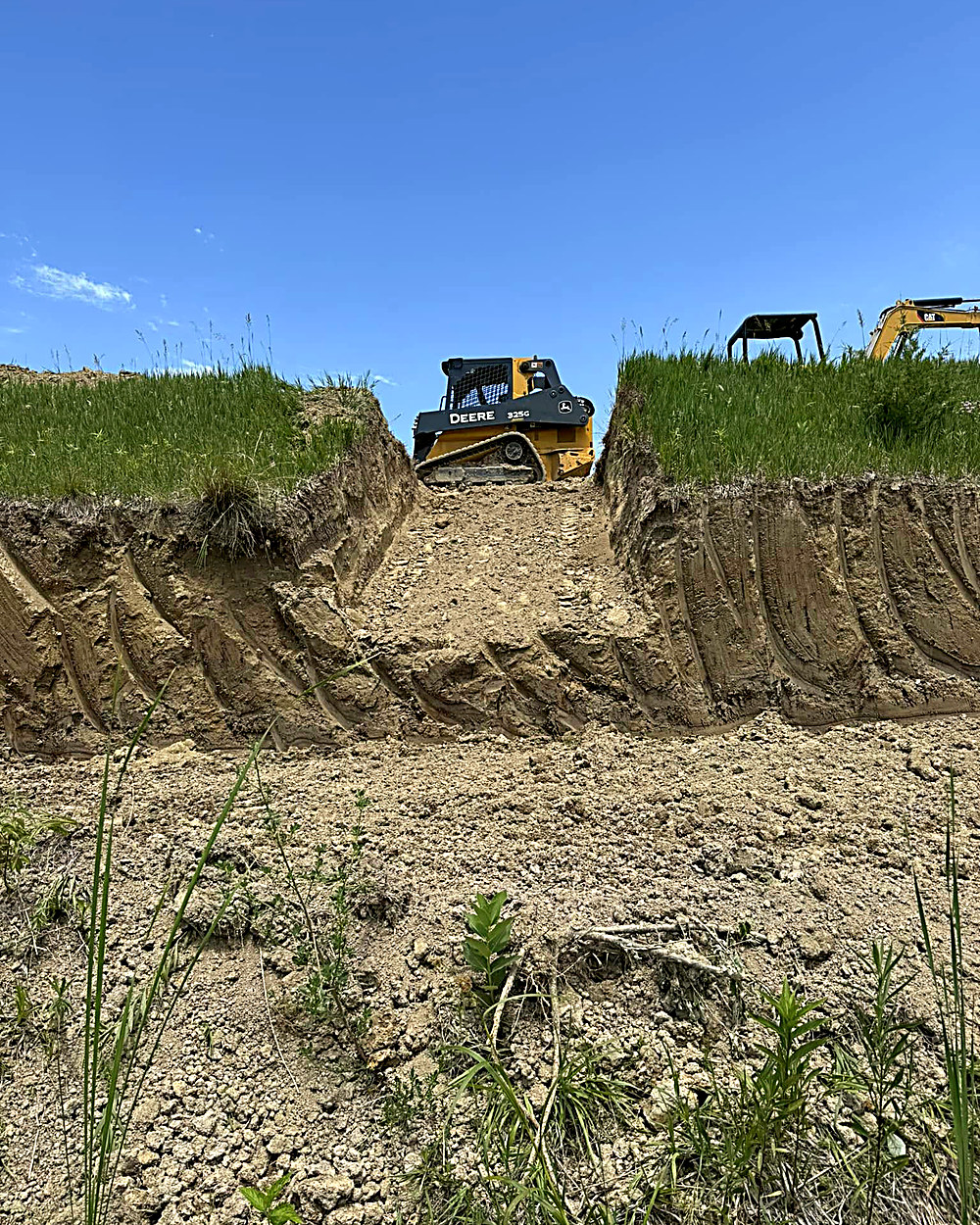 Skid steer working a cut bank of loess soil on a Mills County acreage
